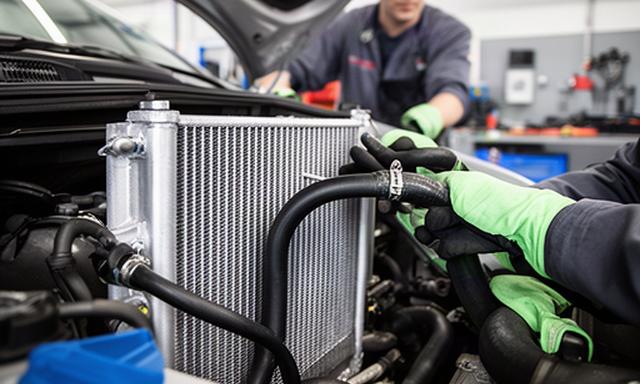 Automotive radiator and cooling hoses being checked by a technician in the shop